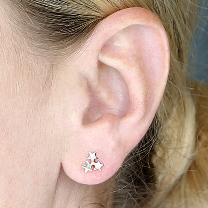 Close-up of an ear wearing silver star-shaped earrings.